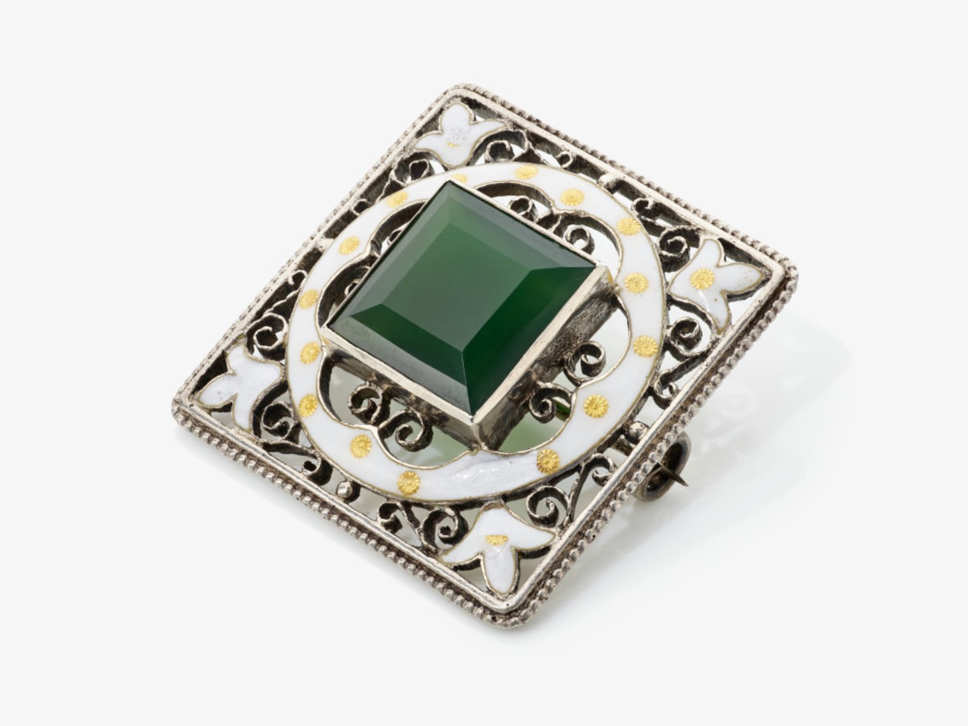 A brooch with green glass stone and white enamel