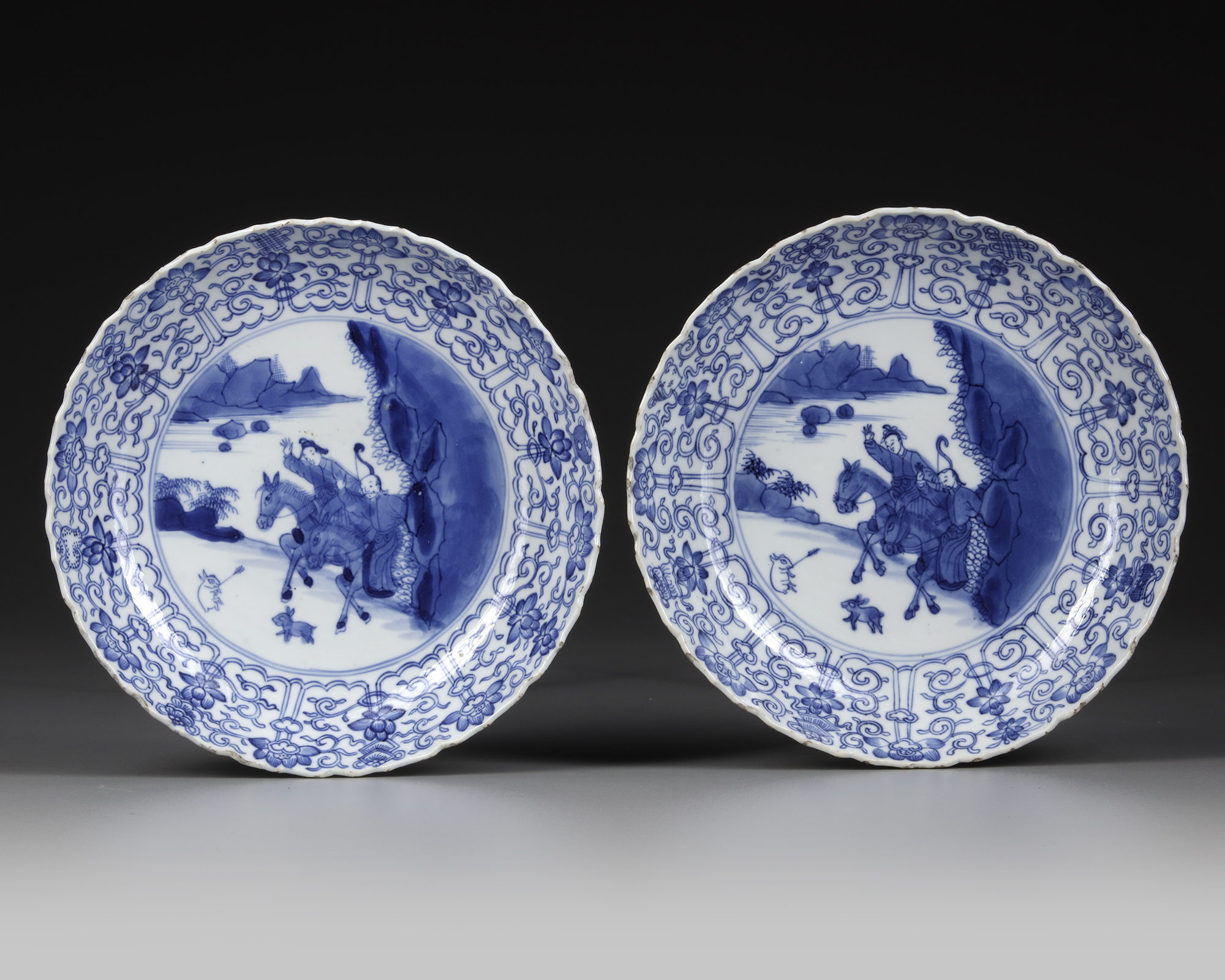 A PAIR OF CHINESE BLUE AND WHITE 'HUNTING' DISHES, KANGXI PERIOD (1662-1722)