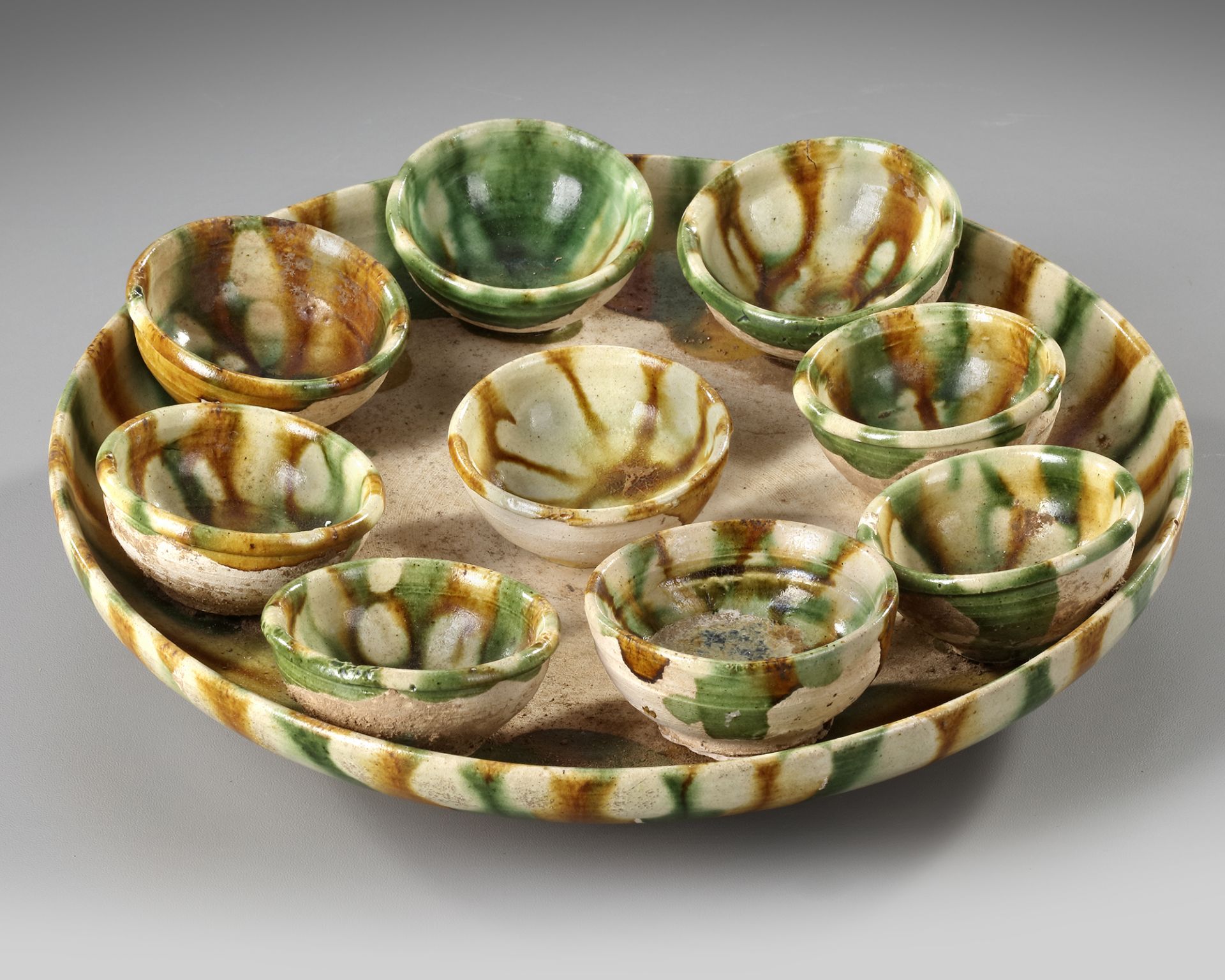 A CHINESE SANCAI GLAZED TRAY AND NINE CUPS, TANG DYNASTY (618-906 AD)