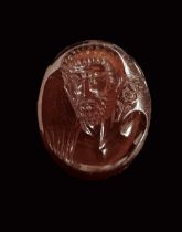 A ROMAN INTAGLIO OF A FACING MAN IN BROWN GARNET, 1ST CENTURY AD