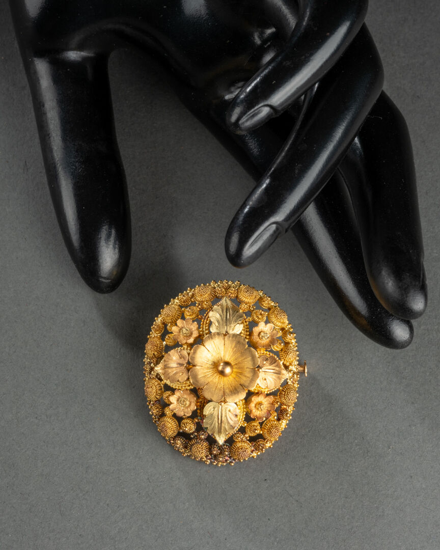 BROCHE ovale à motifs de fleurs et feuillages Métal doré, ciselé et ajouré H. 4 cm - L. 3,5 cm