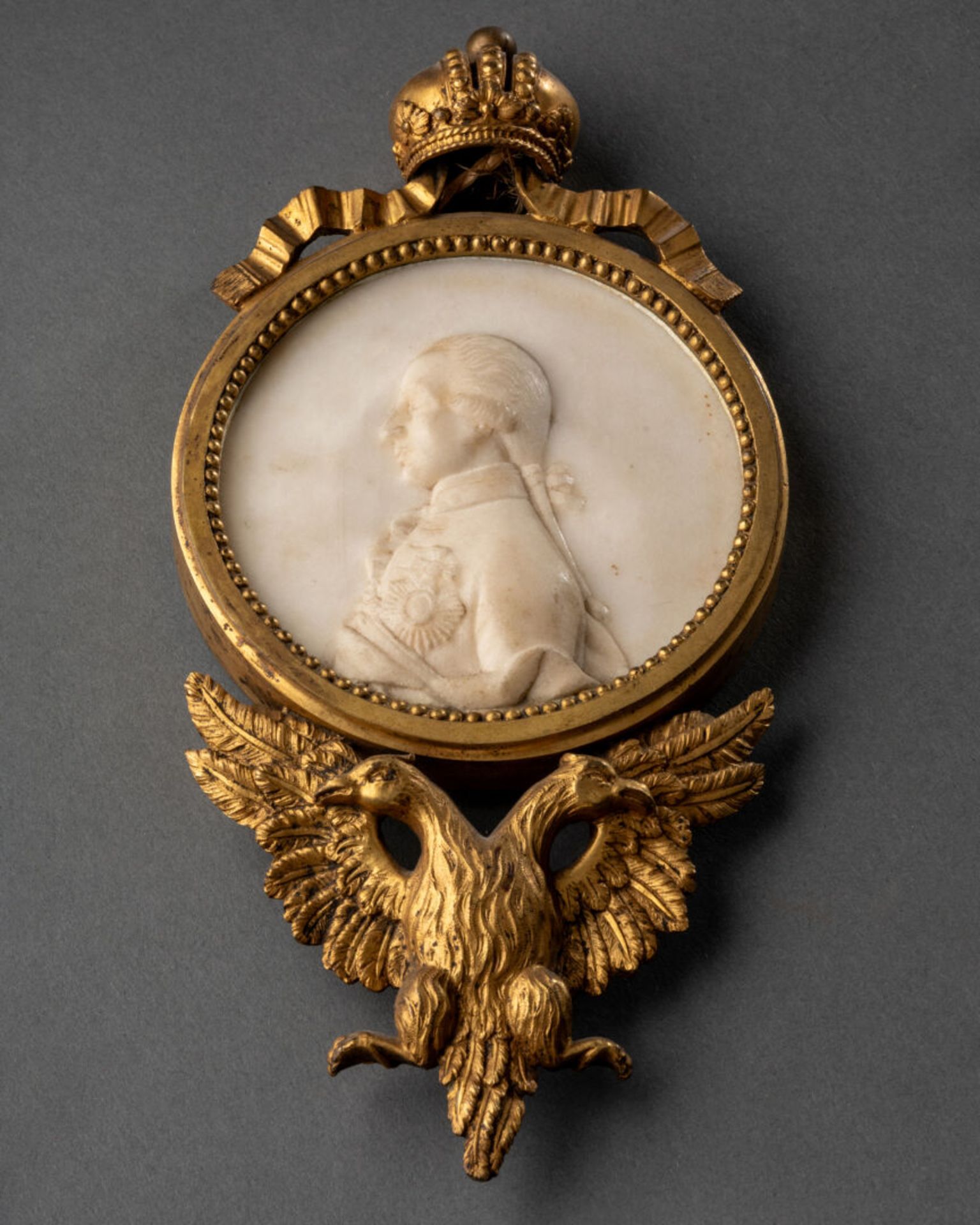 MEDAILLON figurant un profil royal Marbre sculpté en bas-relief, encadrement de bronze sommé d'une