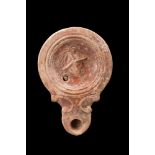 ROMAN ORANGE TERRACOTTA OIL LAMP WITH A GLADIATOR'S HEAD