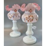 A pair of Victorian opaline glass vases, having pink frilled shade above a hand painted white floral