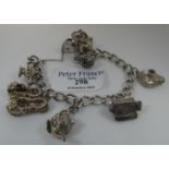 A silver charm bracelet with various charms including a hedgehog, lamp, pair of slippers etc. (B.