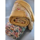Two vintage quilts; one with a floral print and the other a cotton patchwork on a mustard ground