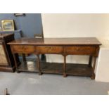 Early 19th century Welsh oak dresser base, the moulded top above three drawers with brass swan