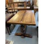 Early 20th century oak extending dining table on large ornately carved and fluted pedestals,