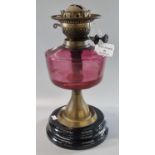 Early 20th century double oil burner missing its chimney and shade having Cranberry glass