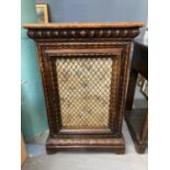 Early 20th century ornately carved oak single door cabinet with mesh and fabric panel, the