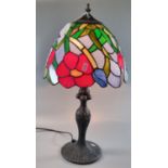 Tiffany style table lamp with multicoloured floral and foliate shade on a naturalistic circular