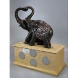 Pair of composition amorous elephants on a wooden plinth with 'Push the wheels of Industry 1933'