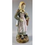 Continental majolica figurine of an old lady in bonnet with basket of flowers, standing on a