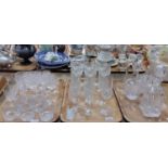 Three trays of glassware, to include: three decanters with stoppers in different shapes, champagne