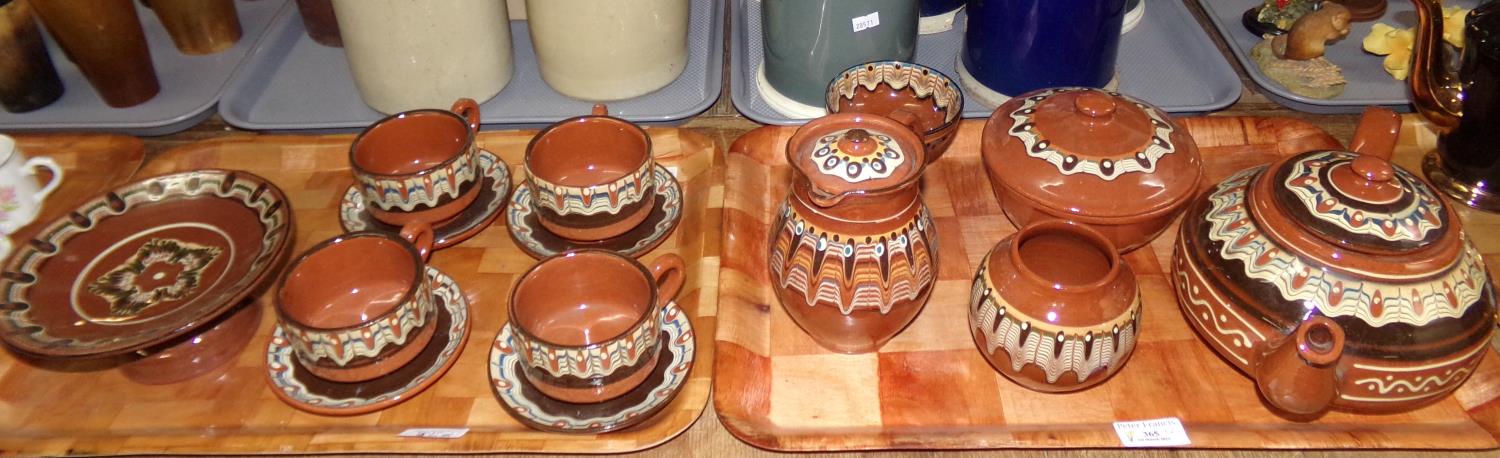 Two trays of slipware pottery items, to include: teapot, cups and saucers, lidded jug, pedestal