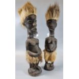 Pair of African carved wooden female figures with natural fur headdresses and skirts. 38cm high