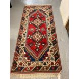 Hand woven probably Turkish red ground runner decorated with stylised flowerheads and two taratalu