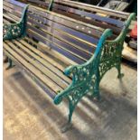 Pair of weathered slatted garden benches with green painted cast metal scroll decorated and