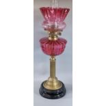 Early 20th century double oil burner lamp having cranberry glass shade above a cranberry glass