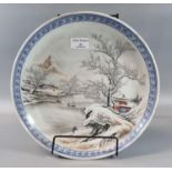 Chinese porcelain small charger with a motif depicting figures, trees and buildings in a snow