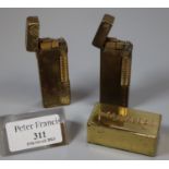 Two brass Dunhill lighters and a brass "Cascades" paperweight. (3) (B.P. 21% + VAT)