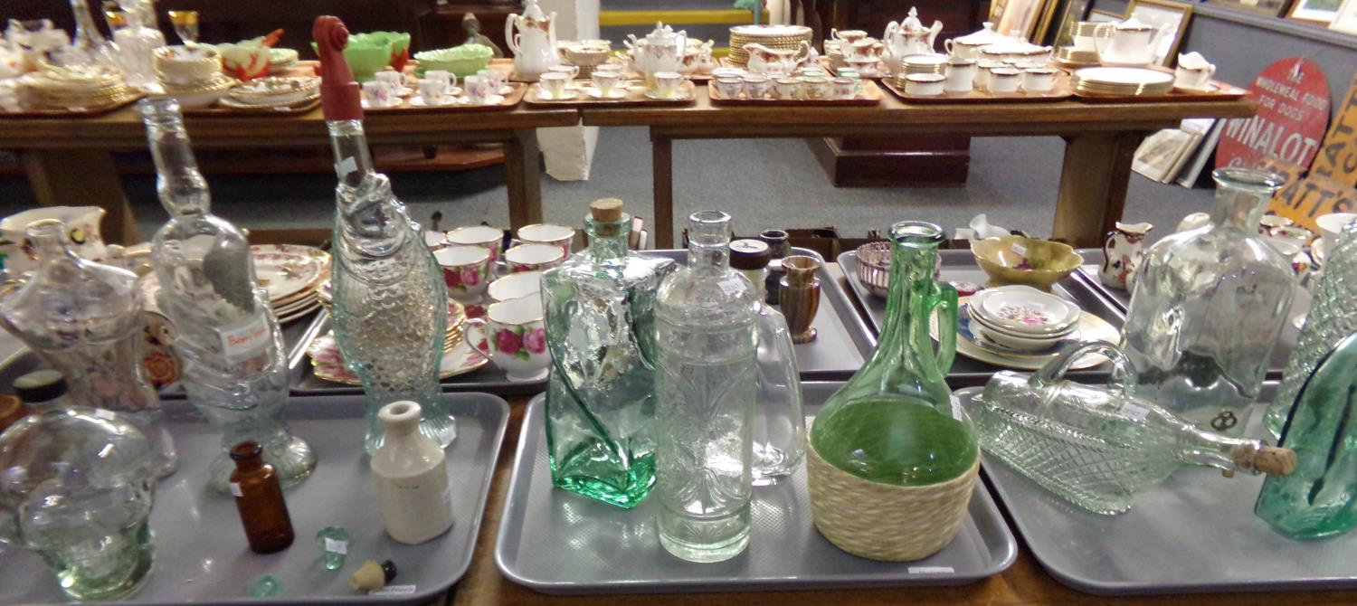 Three trays of assorted glassware: novelty bottles in the shape of a fish, a male torso, skull, hand