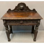 Victorian oak ornately carved side table, the shaped gallery back with carved mask head above a