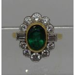 A large emerald and diamond cluster ring. The oval emerald approx 9x6mm surrounded by ten