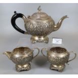 Three piece Indian Silver tea service comprising: bullet shaped teapot with ebonised turned