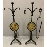 Pair of wrought iron Arts and Crafts fire dogs, both decorated with circular brass panels/plaques of