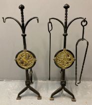 Pair of wrought iron Arts and Crafts fire dogs, both decorated with circular brass panels/plaques of