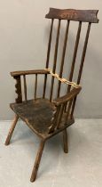 Primitive design stick back armchair on moulded saddle seat, carved 'Gelli'. 111cm high approx. (B.