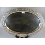 Silver Indian shallow tray of oval form, overall decorated with flowerheads, scroll work and