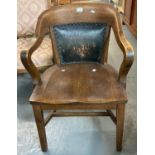 Early 20th century oak captains type chair with leather back and metal stud work on a moulded seat