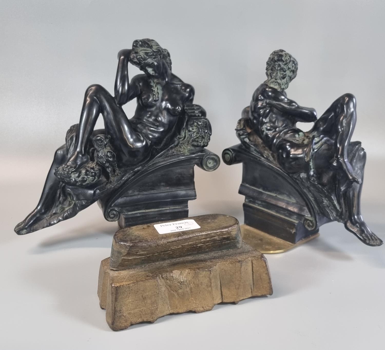 Pair of black moulded composition figures in Romanesque style, reclining on scrolled arches,