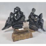 Pair of black moulded composition figures in Romanesque style, reclining on scrolled arches,