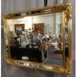 Modern gilt framed mirror of rectangular form with mirrored glass panels and moulded flower head and