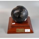 Possibly 16th century iron cannon ball on modern wooden plinth bearing brass plaque inscribed '