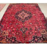 Red ground Persian Mashad carpet decorated with flowers and foliage. 300x205cm approx. (B.P. 21% +