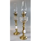 Pair of early 20th century single oil burner lamps having glass reservoir on a brass baluster