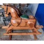 Modern laminated wooden rocking horse with leather seat pad and bridal on swing frame. Natural