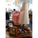 Two carved wooden table lamps in the form of elephants with shades and two small mantel clocks;