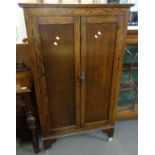 Early 20th century oak two door blind panelled cabinet on wheels, the interior revealing three