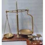 Pair of early 20th century brass shop balance scales with brass pans on mahogany base together