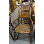 Early 20th century simulated rosewood rocking armchair having entwined spindle back and cane