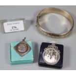 Cardboard box comprising three silver items: bangle, football fob and a religious coin in mount