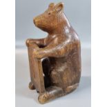 Early 20th Century Black Forest style carved seated bear with glass eyes (one missing), holding a