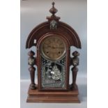 Early 20th century walnut architectural mantle clock with mask head mounts, pendulum and two
