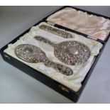 Three piece silver repoussé dressing table set comprising: two brushes and a hand mirror. (B.P.