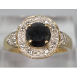 Modern 18ct gold black and white diamond ring, the central black diamond surrounded by a cluster